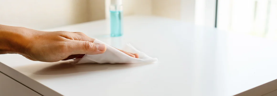 Hand reinigt Tisch mit Tuch